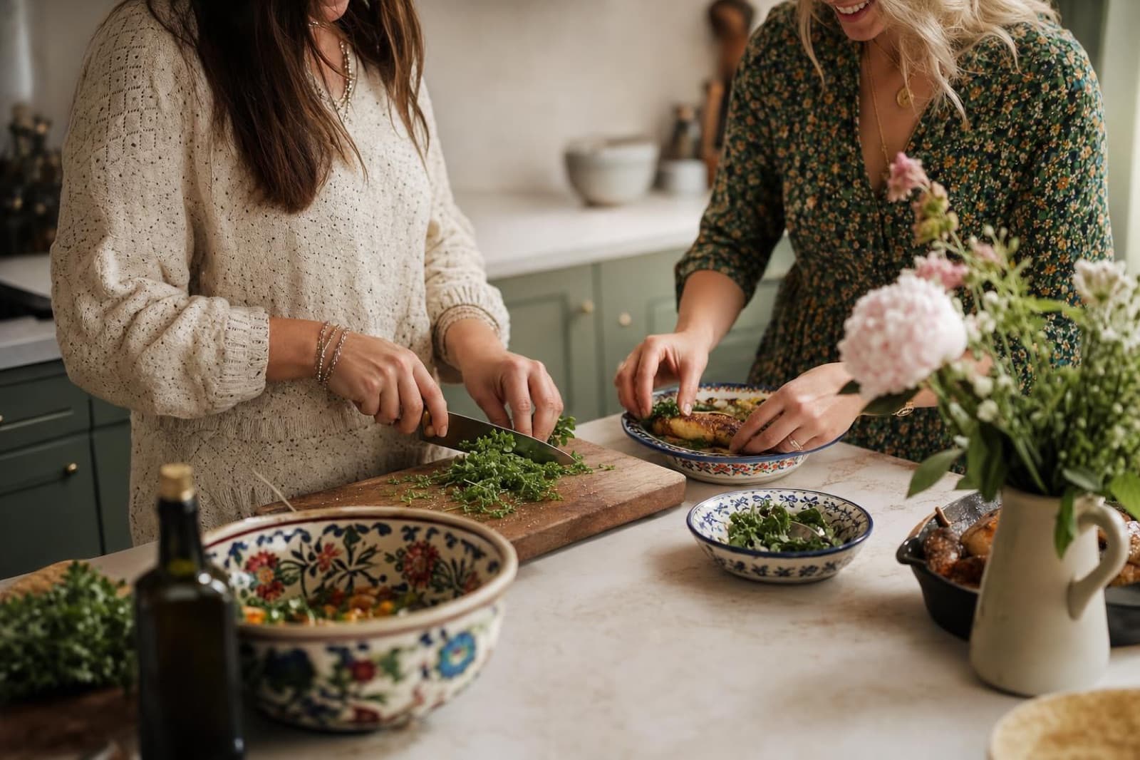 Two guests cooking side by side, chopping fresh herbs and plating food