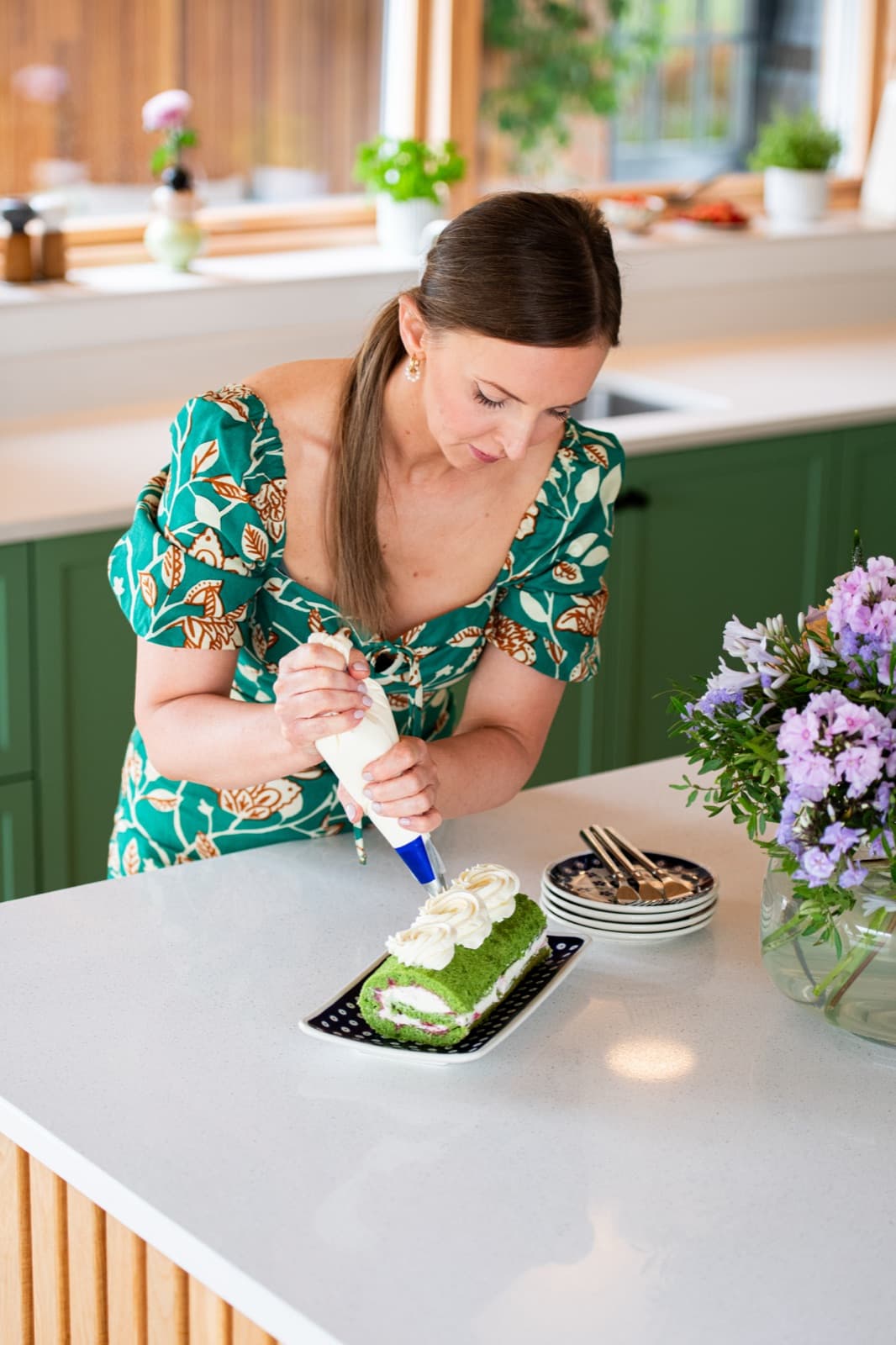 Kasha piping cream onto a pistachio roulade at the kitchen island
